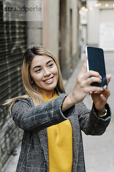 Junge Frau macht Selfie mit ihrem Smartphone in der Stadt