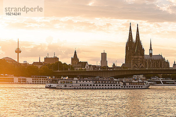 Deutschland  Nordrhein-Westfalen  Köln  Untergehende Sonne beleuchtet Ausflugsschiff vor der Deutzer Hängebrücke