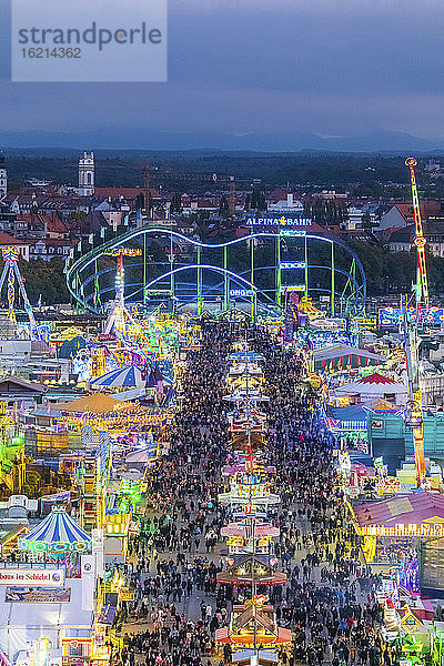 Deutschland  Bayern  München  Drohnenaufnahme von Menschenmassen  die in einem großen Vergnügungspark in der Abenddämmerung das Oktoberfest feiern
