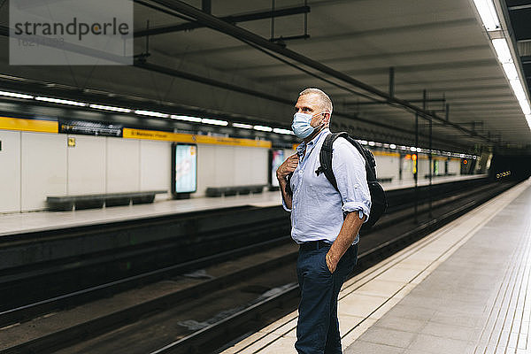 Geschäftsmann mit Gesichtsmaske auf dem Bahnsteig einer U-Bahn