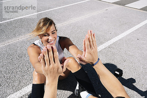 Lächelnde Frau  die ihrem Freund beim Sport auf der Straße in der Stadt die Daumen drückt
