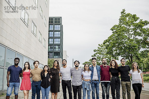 Selbstbewusste weibliche und männliche Freunde stehen gegen den klaren Himmel in der Stadt