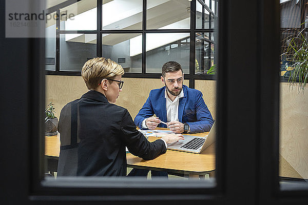 Geschäftskollegen planen eine Strategie  während sie in einem Sitzungssaal über einen Laptop diskutieren