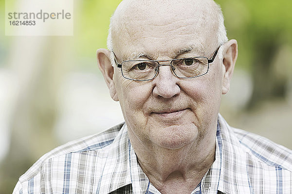 Deutschland  Nordrhein-Westfalen  Köln  Porträt eines älteren Mannes mit Brille im Park  lächelnd