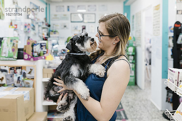 Glückliche Frau  die einen Schnauzer trägt  während sie in einem Zoosalon steht