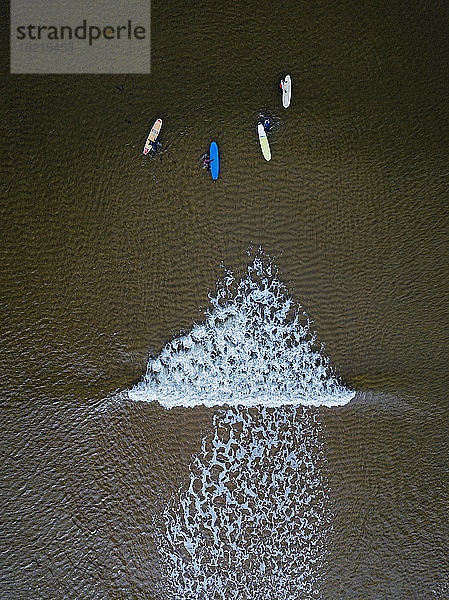Luftaufnahme von Menschen beim Surfen im braunen Wasser der Barentssee