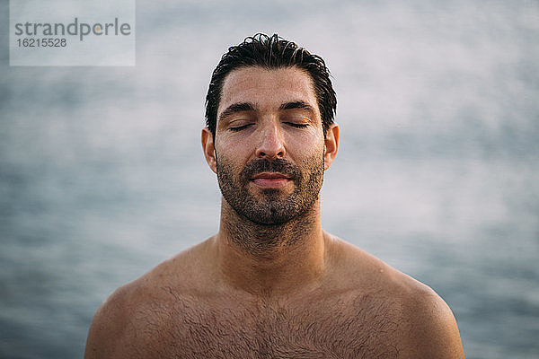 Nahaufnahme eines attraktiven Mannes ohne Hemd mit geschlossenen Augen am Meer