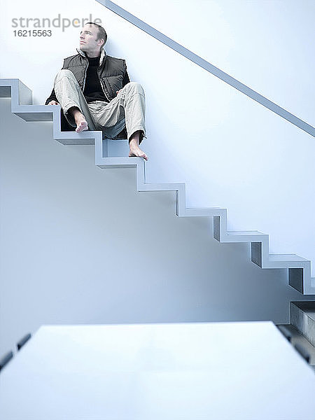 Junger Mann auf einer Treppe sitzend  tiefer Blickwinkel