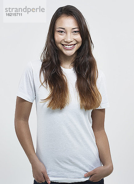 Porträt einer jungen Frau vor weißem Hintergrund  lächelnd