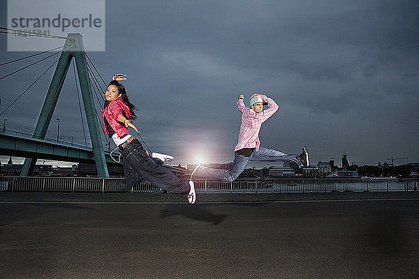 Deutschland  Köln  Mann und Frau springen  Skyline im Hintergrund
