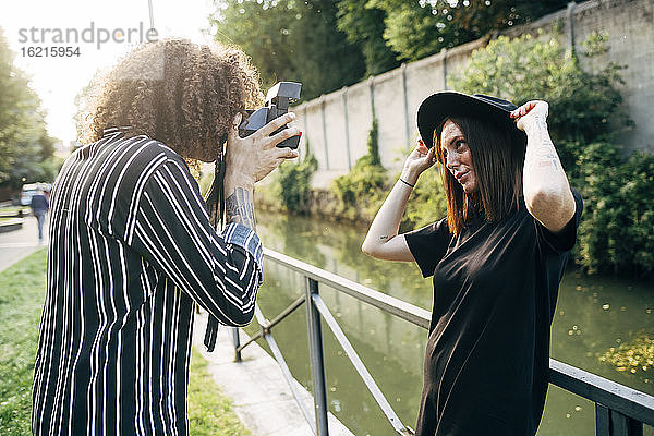 Mann fotografiert seine Freundin mit der Kamera  während er im Park steht