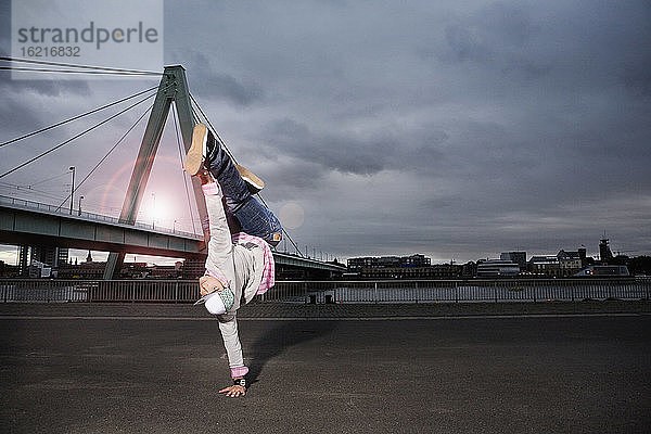 Deutschland  Köln  Junger Mann beim Breakdance  Rheinbrücke im Hintergrund