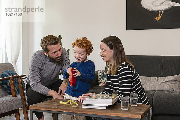 Süßer Junge zeigt Spielzeugroboter lächelnden Eltern im Wohnzimmer zu Hause