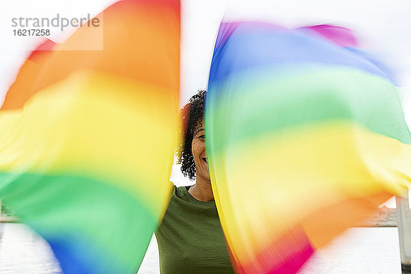 Nahaufnahme einer erwachsenen Frau  die Regenbogenfahnen schwenkt  während sie in der Stadt steht