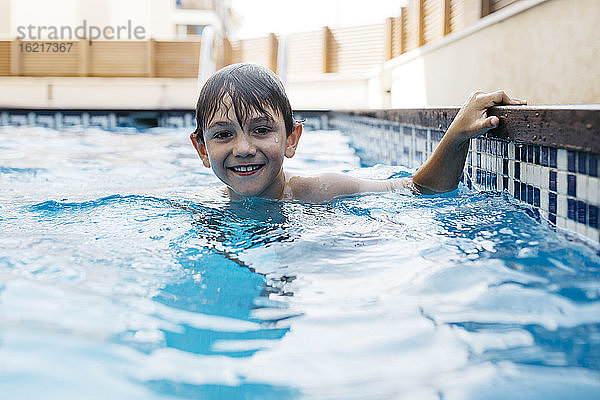 Lächelnder Junge  der sich im Sommer im Schwimmbad vergnügt