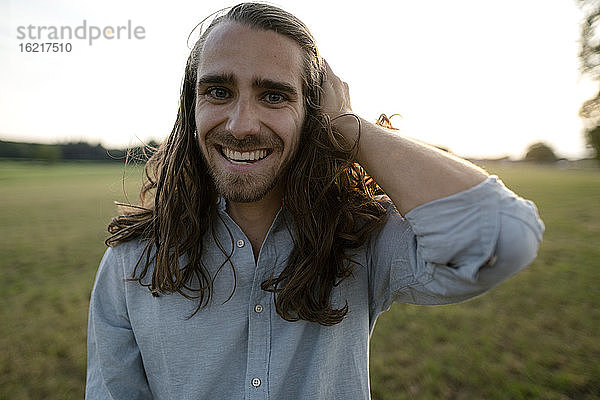 Porträt eines glücklichen jungen Mannes auf einer Wiese auf dem Lande