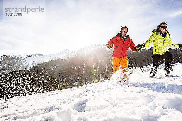 Unbekümmertes Paar beim Laufen durch den Schnee  Achenkirch  Österreich