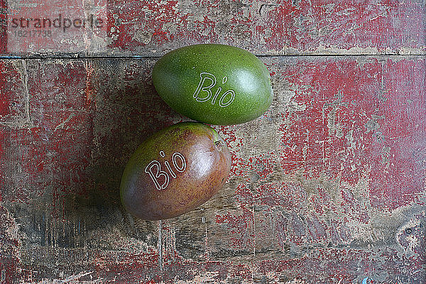 Zwei Mangofrüchte auf einer verwitterten Holzfläche liegend