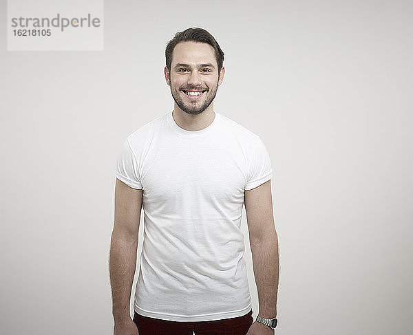 Porträt eines jungen Mannes vor weißem Hintergrund  lächelnd