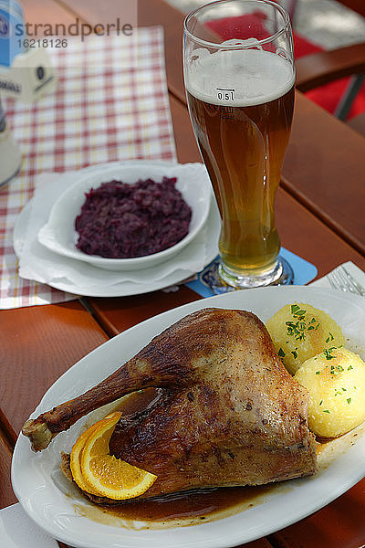 Deutschland  Bayern  Teller mit Fleisch und Bierglas auf Holztisch  Nahaufnahme