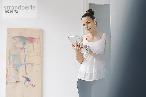 Geschäftsfrau  die ein digitales Tablet benutzt  während sie in einem Loft an der Wand steht