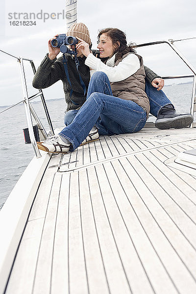 Deutschland  Ostsee  Lübecker Bucht  Junges Paar auf Boot  Mann schaut durch Fernglas