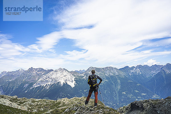 Wanderer steht auf dem Gipfel und schaut auf die Berge  Westliche Rätische Alpen  Sondrio  Italien