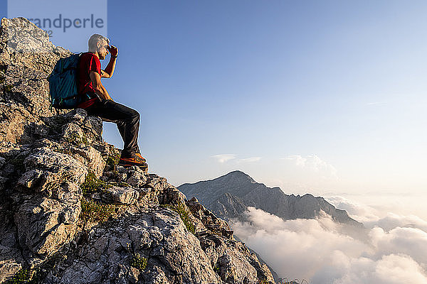 Wanderer betrachtet die Aussicht  während er auf einem Berg in den Bergamasker Alpen  Italien  sitzt