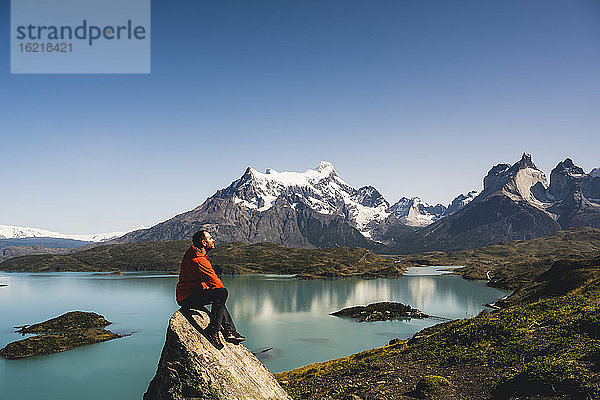 Mann sitzt auf einem Felsen am Pehoe-See im Torres Del Paine-Nationalpark  Chile Patagonien  Südamerika
