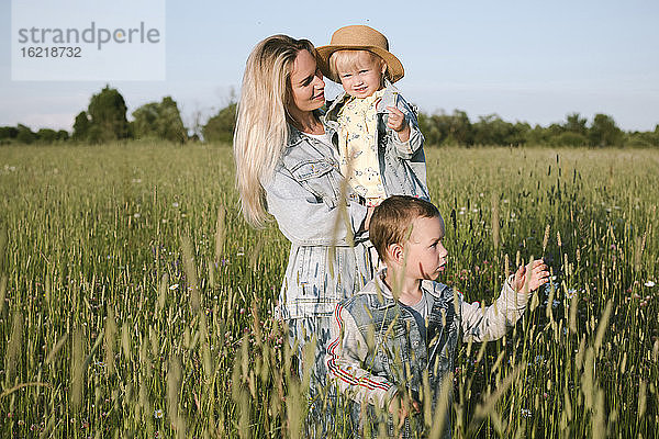 Lächelnde Mutter mit zwei Kindern auf einem Feld