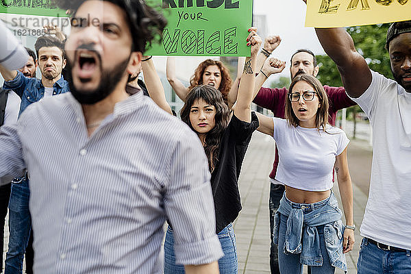 Multiethnische Menschen mit Transparenten protestieren auf einer Straße in der Stadt