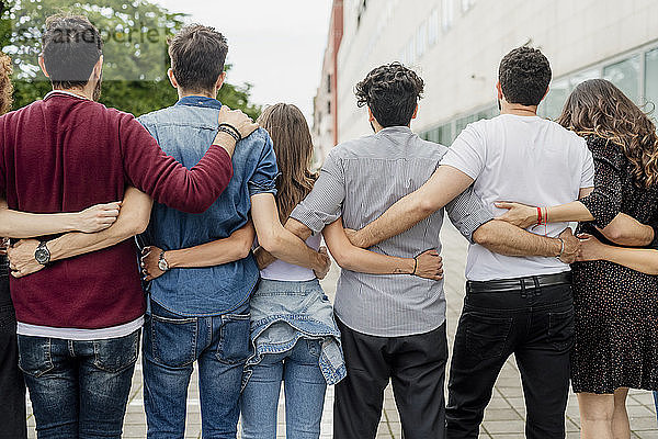 Männliche und weibliche Freunde  die sich umarmen und auf einem Fußweg in der Stadt stehen