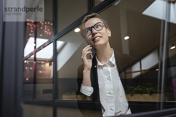 Schöne Geschäftsfrau  die mit dem Handy telefoniert  während sie im Büro wegschaut