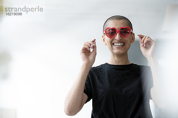 Porträt einer fröhlichen Frau mit herzförmiger Sonnenbrille
