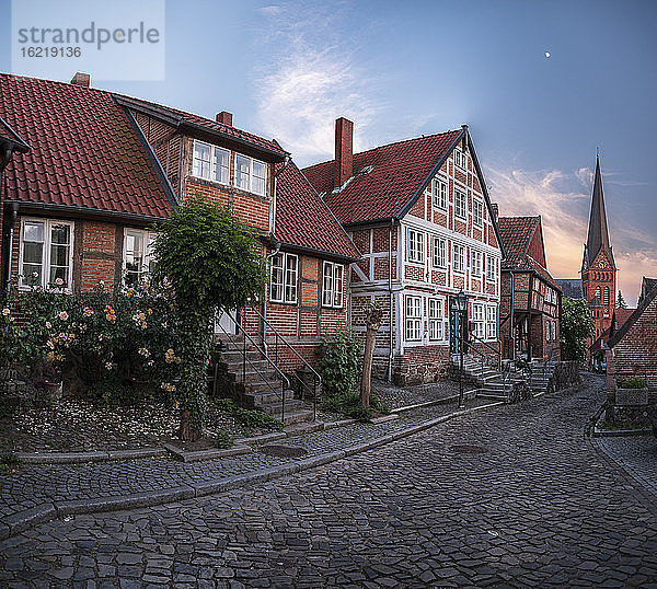 Deutschland  Schleswig-Holstein  Lauenburg  Häuser entlang einer leeren Kopfsteinpflasterstraße in der Abenddämmerung
