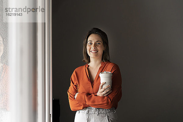 Porträt einer lächelnden Geschäftsfrau mit Kaffeetasse zu Hause