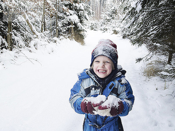 Österreich  Junge spielt mit Schnee im Wald