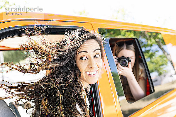 Frau fotografiert andere Frau  die in einem Van sitzt