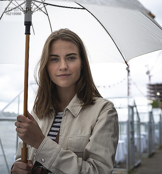Nahaufnahme einer jungen Frau mit Regenschirm in der Stadt