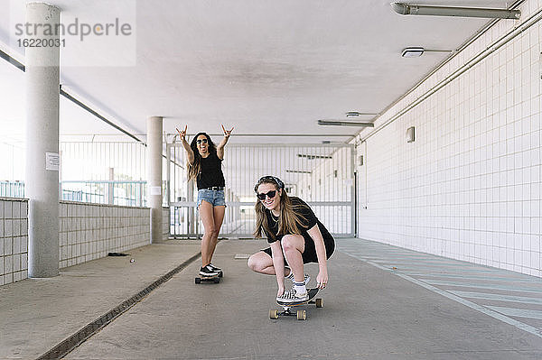 Junge Frau  die in einer Unterführung Skateboard fährt