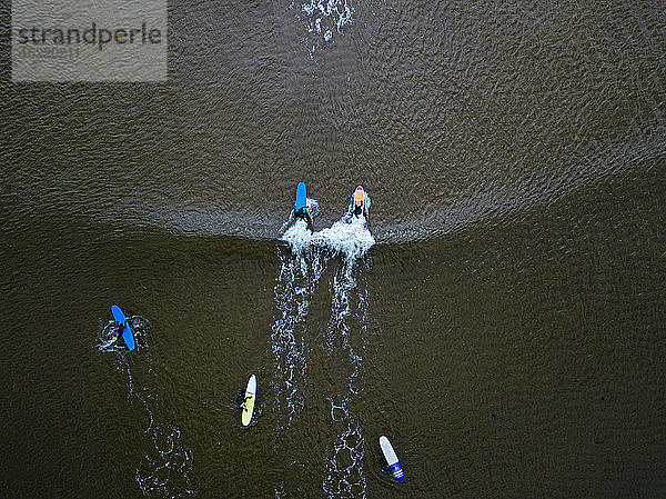 Luftaufnahme von Menschen beim Surfen im braunen Wasser der Barentssee