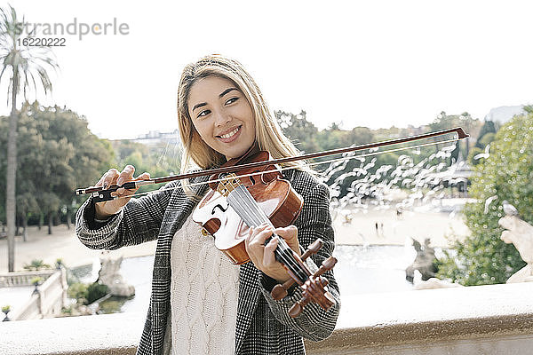 Blonde junge Frau spielt Geige in der Stadt