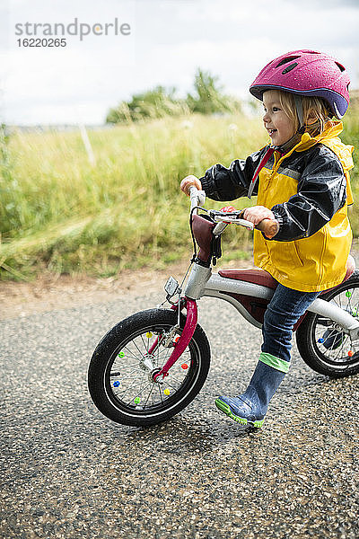 Kleinkind-Mädchen mit rosa Fahrradhelm auf Balance-Fahrrad