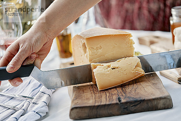 Hände schneiden Käse auf Holz