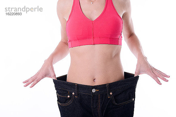 Schöne junge Frau  die nach einem Diätprogramm zur Gewichtsabnahme Hosen in Übergröße ausprobiert.