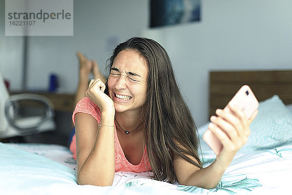 Junger Teenager zu Hause mit einem Smartphone