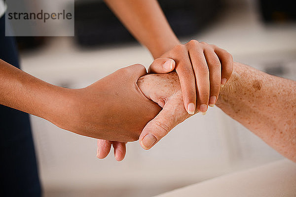 Nahaufnahme einer jungen Person  die zärtlich die Hand einer älteren Frau hält