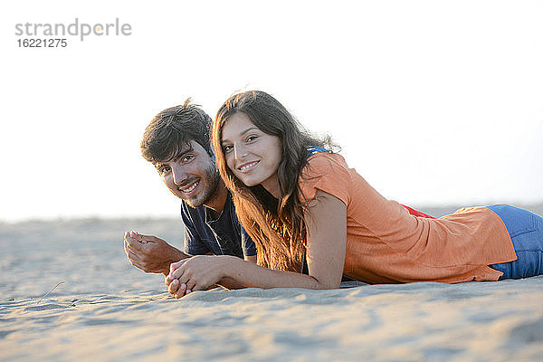 romantisches junges Paar in der Liebe zusammen liegend im Sand am Strand des Mittelmeers Sonnenuntergang