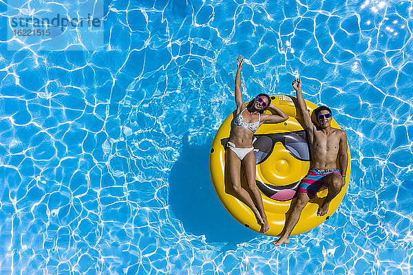 Junges Paar und Smiley-Boje am Pool