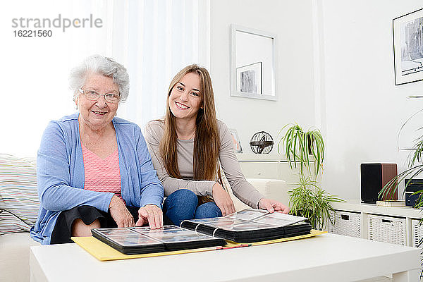 Ältere Frau mit ihrer kleinen Enkelin zu Hause beim Betrachten von Erinnerungen im Familienalbum